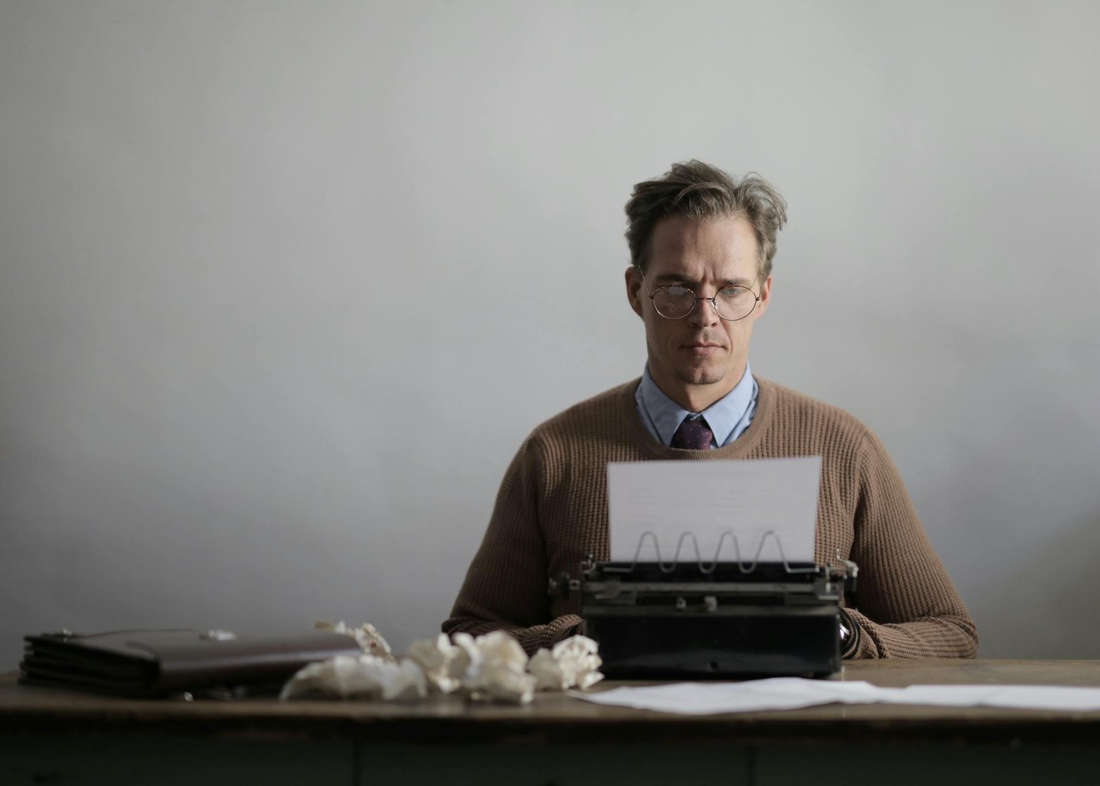 man in brown sweater using a typewriter